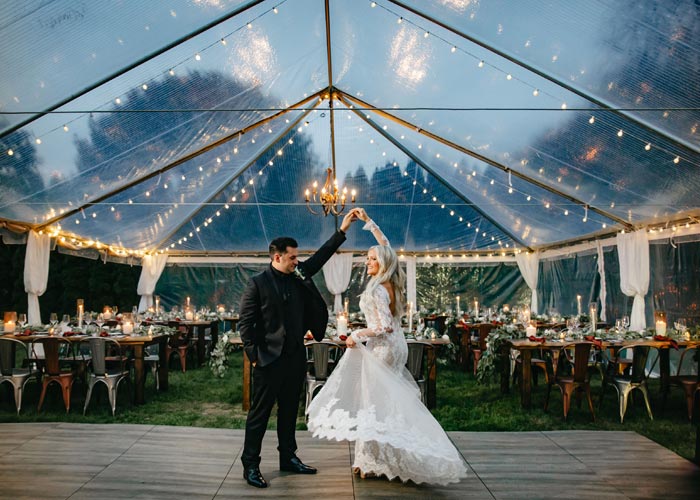a bride and groom dancing under a wedding tent